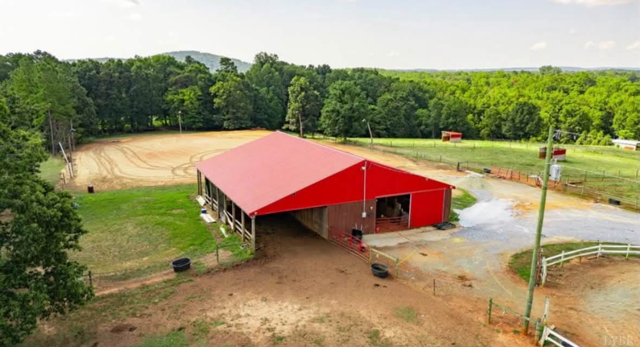 The red-roofed barn and riding arena at Threefold Stables