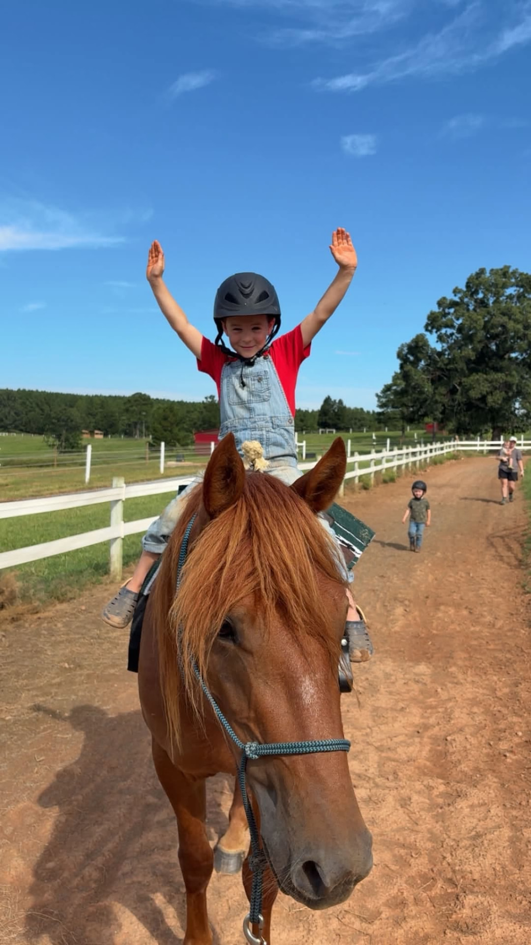 A child riding hands-free with a big smile at Threefold Stables